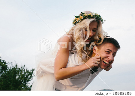 groom carries bride on his back outdoors 20988209