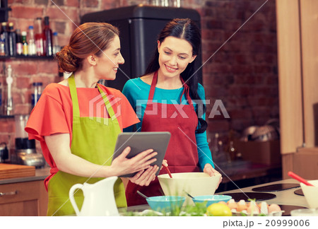happy women with tablet pc cooking in kitchen 20999006