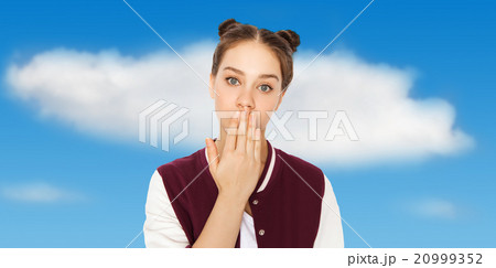 confused teenage girl covering her mouth by hand 20999352