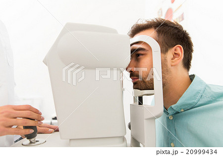 optician with autorefractor and patient at clinic 20999434