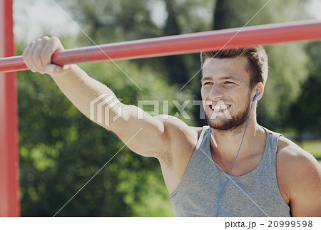 happy young man with earphones and horizontal bar happy young man with earphones and horizontal bar 20999598