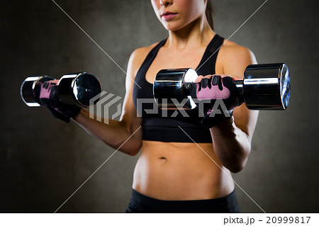 close up of woman flexing arms with dumbbells 20999817