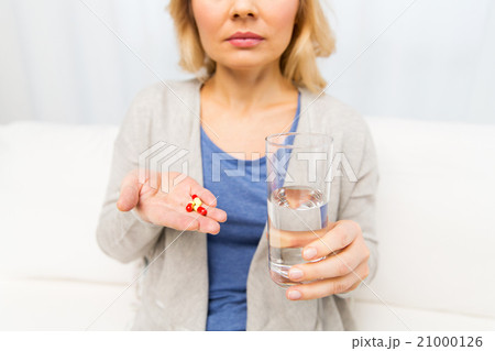close up of woman with medicine and water glass close up of woman with medicine and water glass 21000126