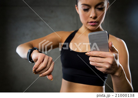woman with heart-rate watch and smartphone in gym woman with heart-rate watch and smartphone in gym 21000138