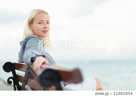 Lady sitting on a bench outdoors Lady sitting on a bench outdoors 21002054
