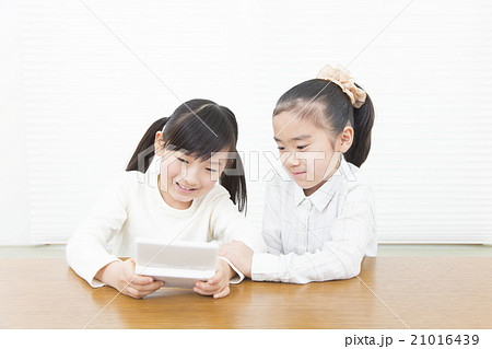 ゲームで遊ぶ女の子 女の子二人 小学生 女の子 二人 ポータブルゲーム 姉妹の写真素材