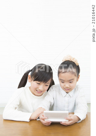 ゲームで遊ぶ女の子 女の子二人 小学生 女の子 二人 ポータブルゲーム 姉妹の写真素材
