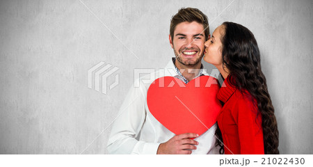 Composite image of man holding paper heart and being kissed by g Composite image of man holding paper heart and being kissed by g 21022430
