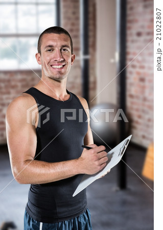 Composite image of smiling sports coach writing on clipboard 21022807