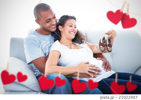 Composite image of couple with baby shoes 21022987