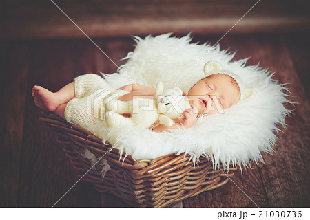 Cute newborn baby in bear hat sleeps in basket with toy teddy be Cute newborn baby in bear hat sleeps in basket with toy teddy be 21030736
