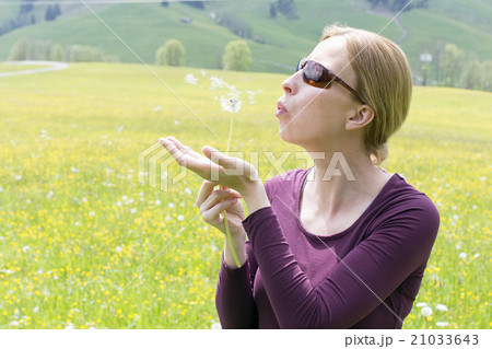 Woman blowing on dandelion Woman blowing on dandelion 21033643