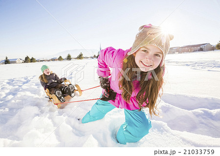 Children (8-9, 10-11) playing with sled in snow 21033759