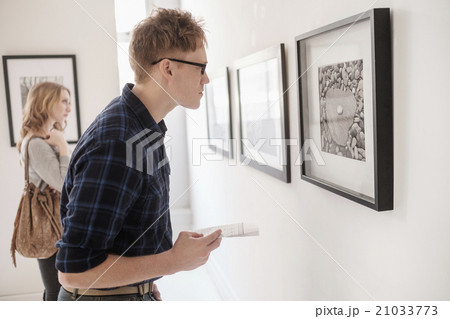 Young couple looking at photographs at museum 21033773
