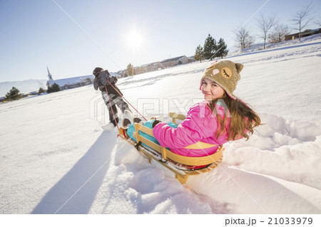 Children (8-9, 10-11) playing with sled in snow 21033979