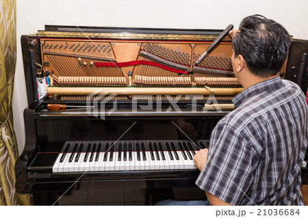 Technician tuning a upright piano using lever Technician tuning a upright piano using lever 21036684
