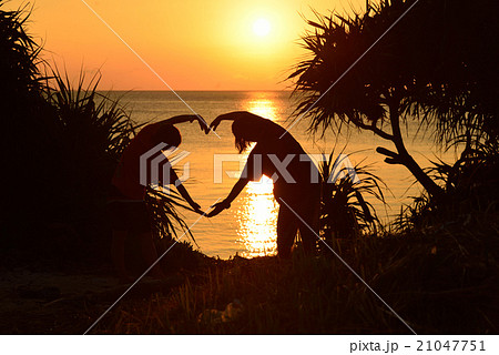 沖縄県　慶良間　手でハートを作る女性二人のシルエット 21047751
