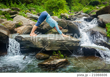 Woman doing yoga oudoors at tropical waterfall 21066606