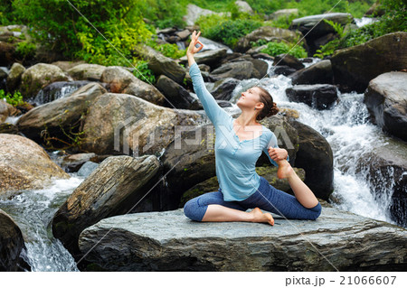 Woman doing yoga outdoors at tropical waterfall 21066607