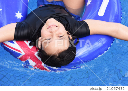 女の子がプールでオーストラリアの国旗柄の浮き輪に浮いてくつろいでるの写真素材