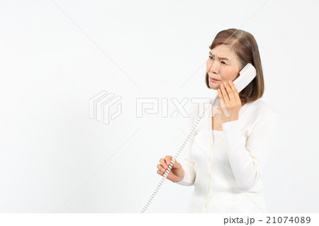 電話をかけて表情が曇るシニア女性 21074089