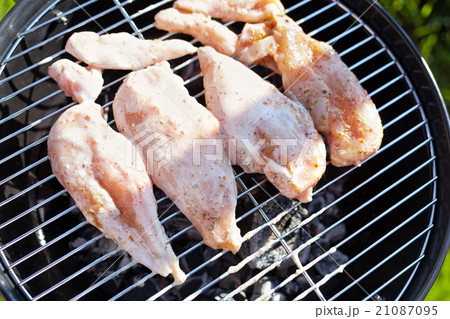 Raw chicken fillet breast cooking on barbeque grid Raw chicken fillet breast cooking on barbeque grid 21087095