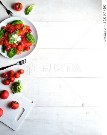 トマトとカッテージチーズとバジルのサラダ 白木材背景の写真素材