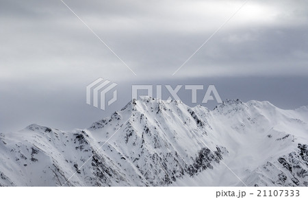 High snowy mountains and gray sky before blizzard High snowy mountains and gray sky before blizzard 21107333