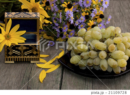 plate with grapes, a casket and a bouquet flowers 21109728