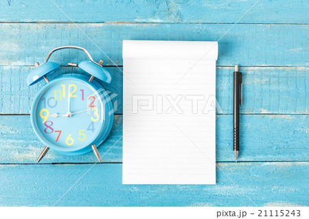 White lined note paper with blue clock on blue wood table for ba White lined note paper with blue clock on blue wood table for ba 21115243