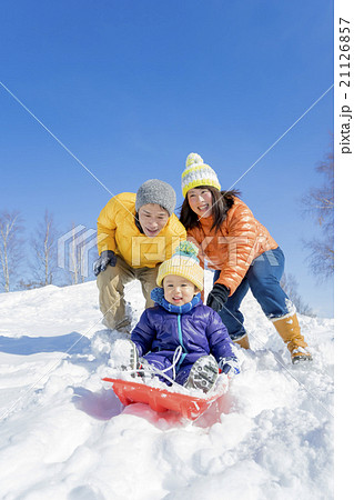 雪の公園でソリ遊びをする3人家族 21126857