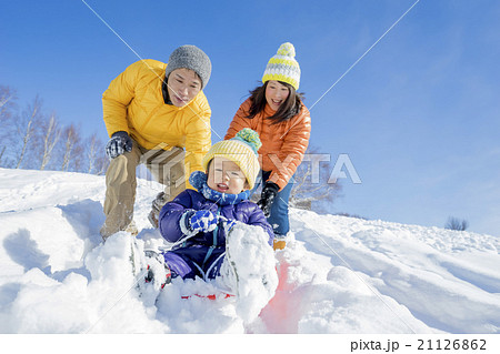 雪の公園でソリ遊びをする3人家族 21126862