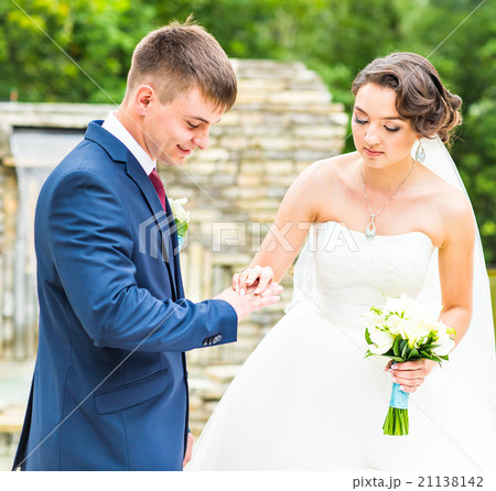 groom and bride is wearing a ring on the finger groom and bride is wearing a ring on the finger 21138142