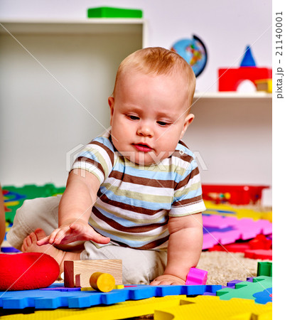 Kid baby boy plying with puzzle toy on floor. 21140001