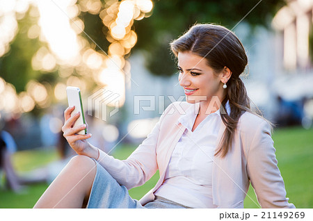 Businesswoman sitting in park checking her 21149269