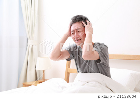 ベッドで頭を抱える中高年男性 21153604