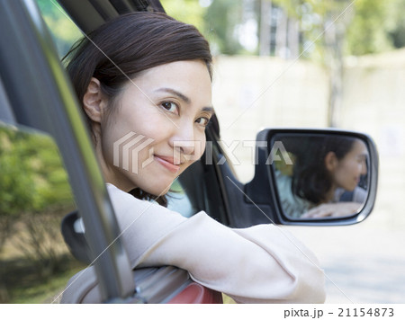 車の窓から顔を出す40代の女性の写真素材