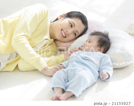 手を繋いで寝る母親と赤ちゃんの写真素材