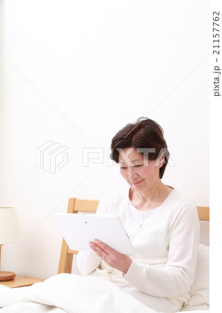 ベッドでタブレットをする60代女性 ベッドでタブレットをする60代女性 21157762