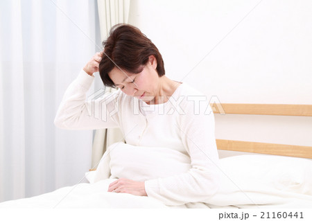 ベッドで頭を抱える中高年女性 21160441