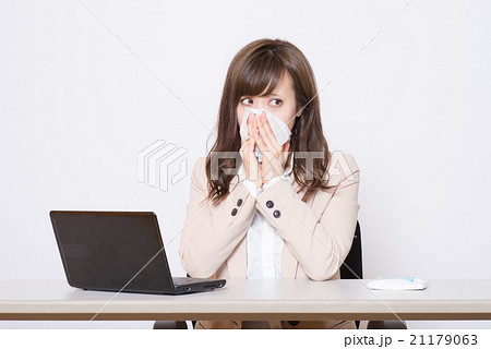 オフィスでティッシュで鼻を押さえる女性 21179063