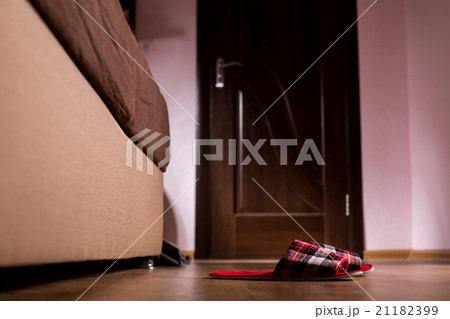 Red checkered slippers beside sofa. 21182399