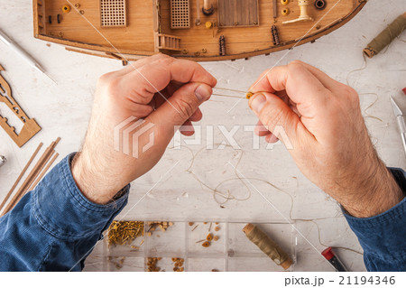 Man collects ship model on a white table 21194346