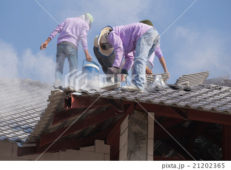 workers installing roof tiles for home building workers installing roof tiles for home building 21202365