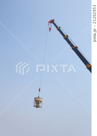Crane lifting concrete mixer container against sky 21202953