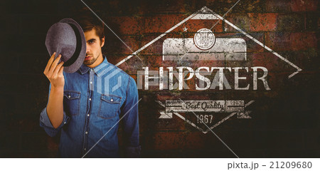 Composite image of portrait of hipster holding hat in front of f Composite image of portrait of hipster holding hat in front of f 21209680