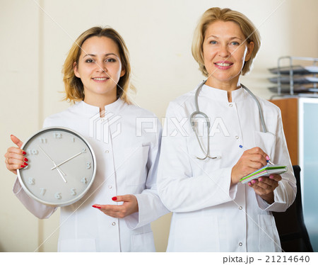 Two female doctors showing time in clock 21214640