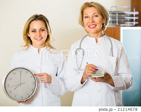 Two female doctors holding clock Two female doctors holding clock 21214678