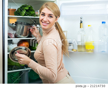 Satisfied housewife near filled fridge Satisfied housewife near filled fridge 21214730