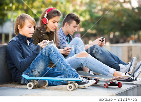 Three teenagers with phones outdoors . 21214755